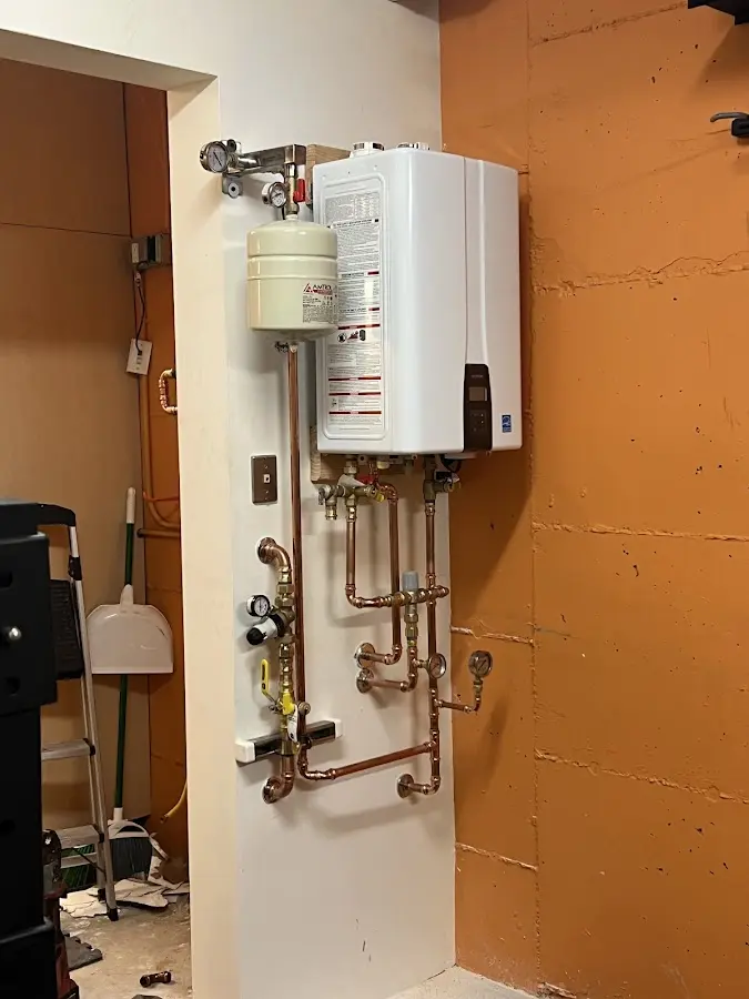 Plumbing technician inspecting water heater connections in Altamont